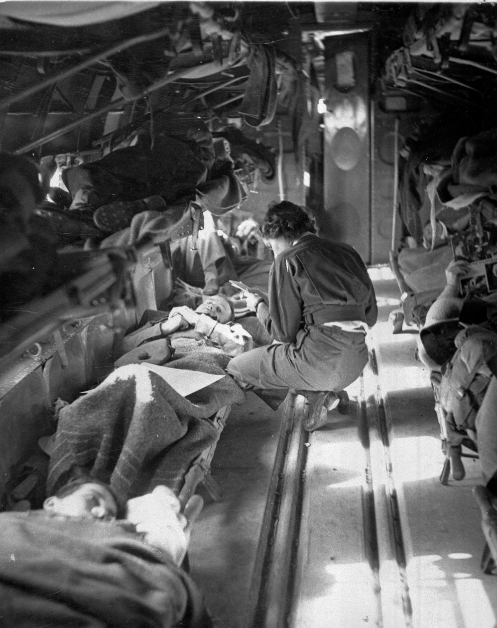 Neiti Mary Smith Etelä-Carolinasta hoitamassa potilaita lennon aikana Pohjois-Afrikkaan, noin 1943-1945, Commando Associationin kokoamasta 650 valokuvan kokoelmasta tekijältä American Photographer