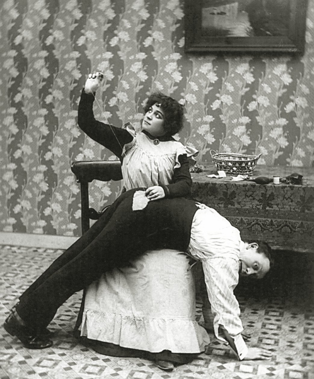 Nainen ompelee repeämän miehen housuihin, n. 1895 tekijältä American Photographer