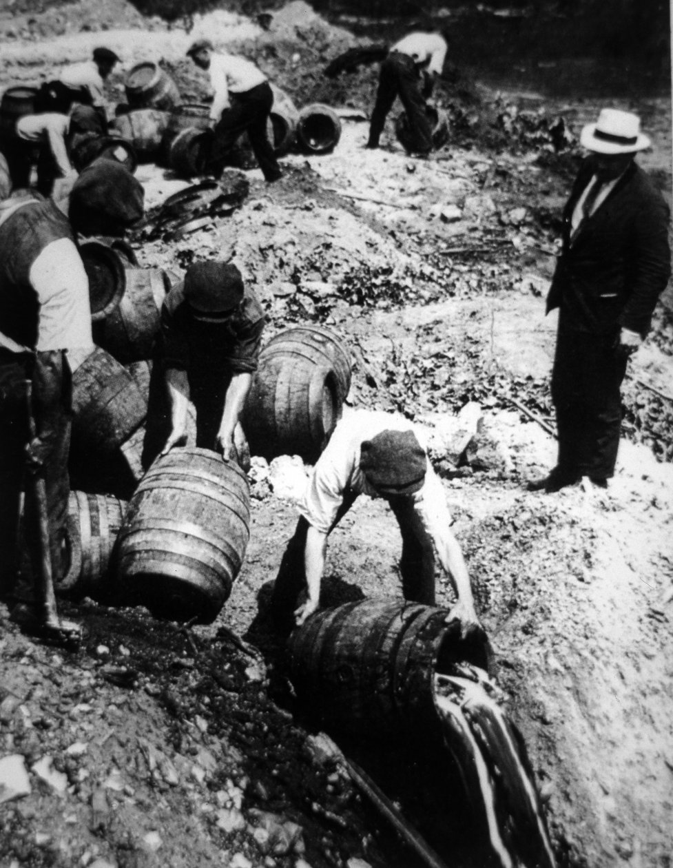 Yhdysvaltain liittovaltion agentti valvoo oluttynnyreiden tuhoamista Amerikan kieltokaudella (1920-33) (m/v kuva) tekijältä American Photographer