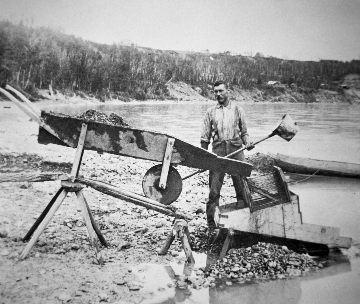 Kaivosmies lastaamassa "rockeria" tai "kehtoa" pesemään kultaa Klondike-joen vedestä Klondiken kultakuumeen aikana (1897-98) 1898 (m/v kuva) tekijältä American Photographer