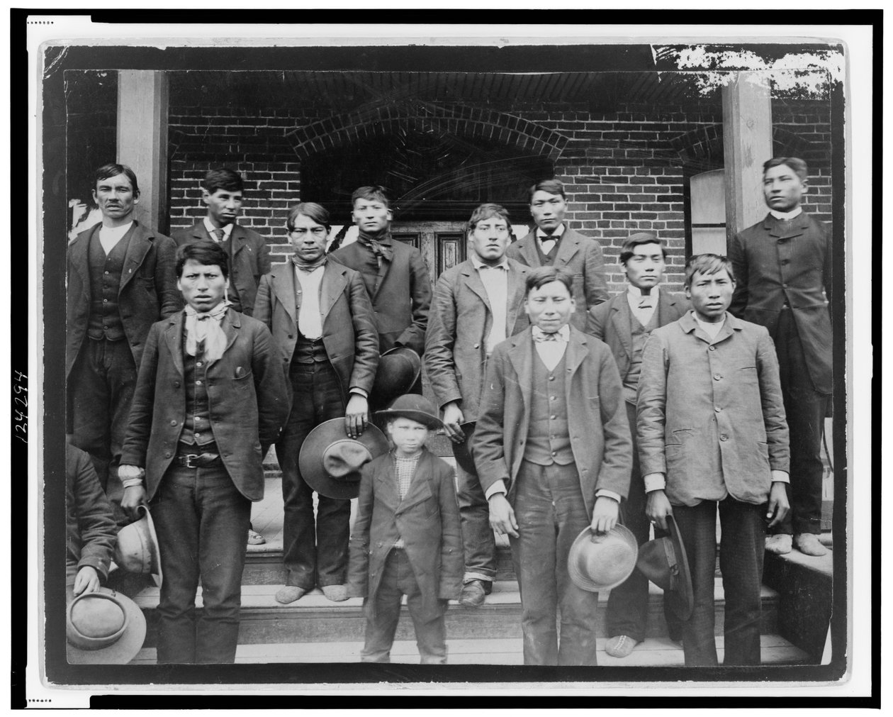 Amerikan intiaanimiehet ja poika poseerasivat Carlisle Indian Schoolin ulkopuolella, Pennsylvaniassa, n. 1890 (valkovalkoinen kuva) tekijältä American Photographer