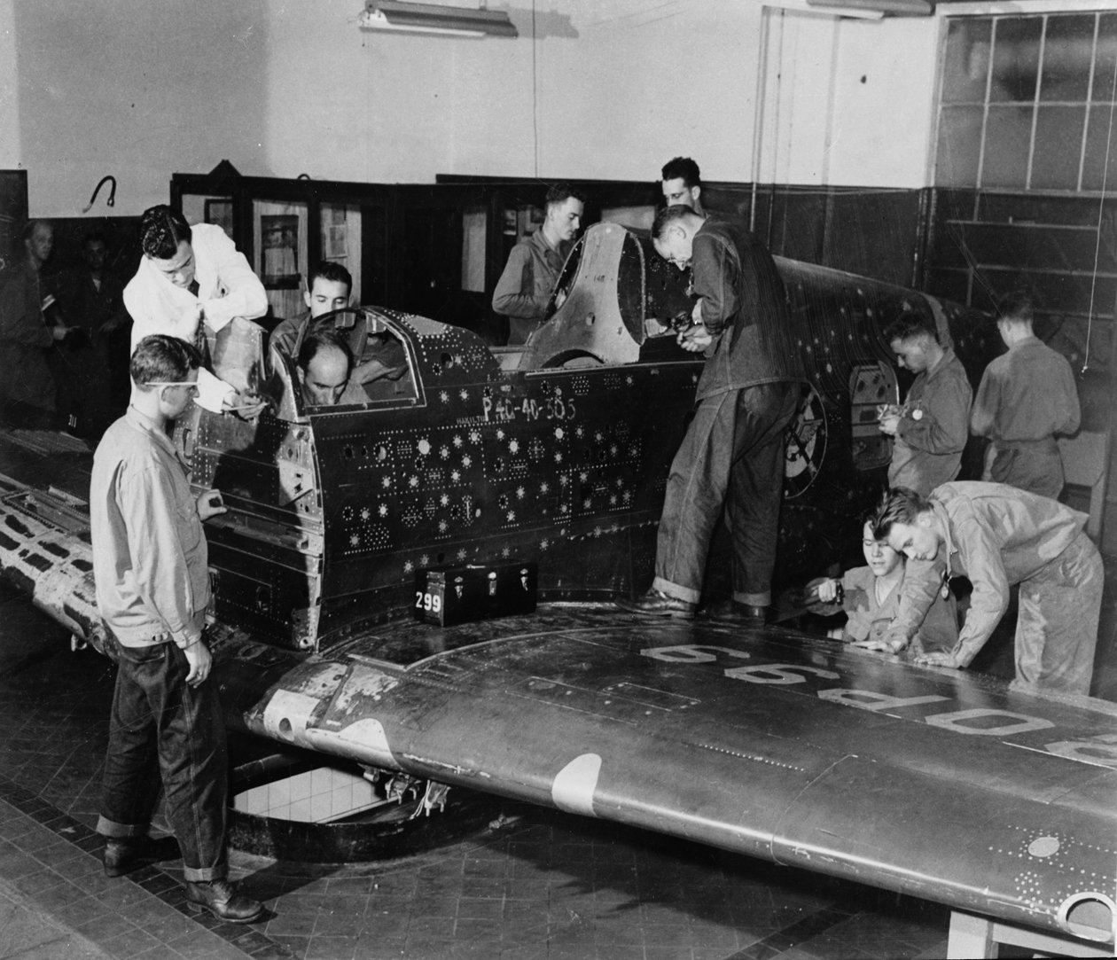 Sotilasharjoittelijat työskentelevät "Flying Patch" -lentokoneessa, Curtiss "Warhawk" -hävittäjäkoneessa ilman moottoria tai häntäkokoonpanoa, simuloiduilla luodinrei