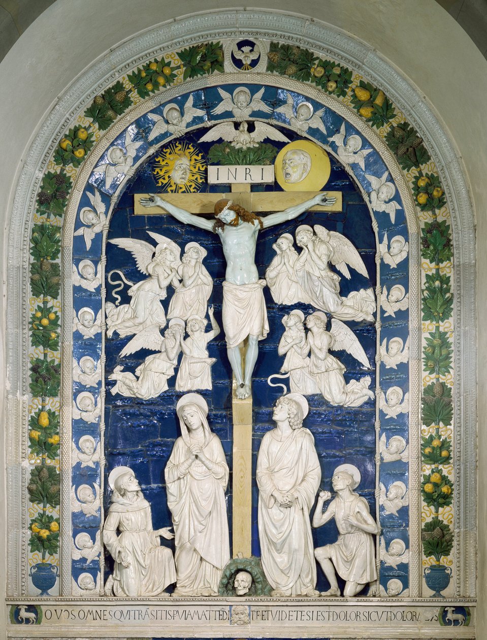 Ristiinnaulitseminen, jossa on pyhä Francois Assisilainen, pyhä Johannes evankelista ja pyhä Hieronymus Ristiin on merkitty INRI (I.N.R.I.). Andrea della Robbian (1435-1525) tekemä korkeareliefikeramiikka noin 1481 Dim. 565x420 cm Santuario della Verna, It tekijältä Andrea Della Robbia