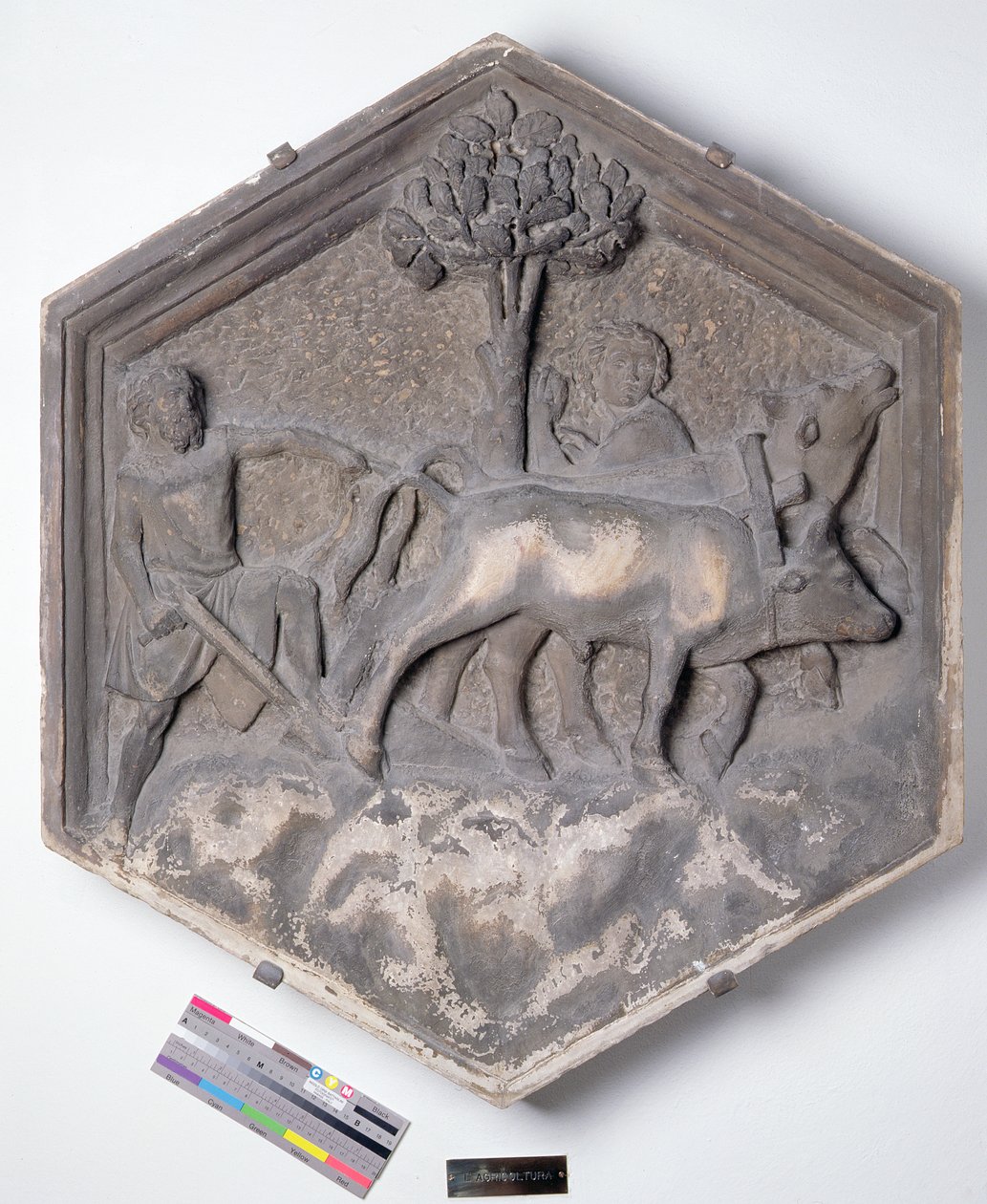 The Art of Agriculture, kuusikulmainen koristeellinen kohokuviolaatta sarjasta, joka kuvaa taiteen ja tieteiden harjoittajia, mahdollisesti perustuen Giotton (n. 1266-1337) n. 1334-1348 (marmori) suunnitelmiin tekijältä Andrea Pisano
