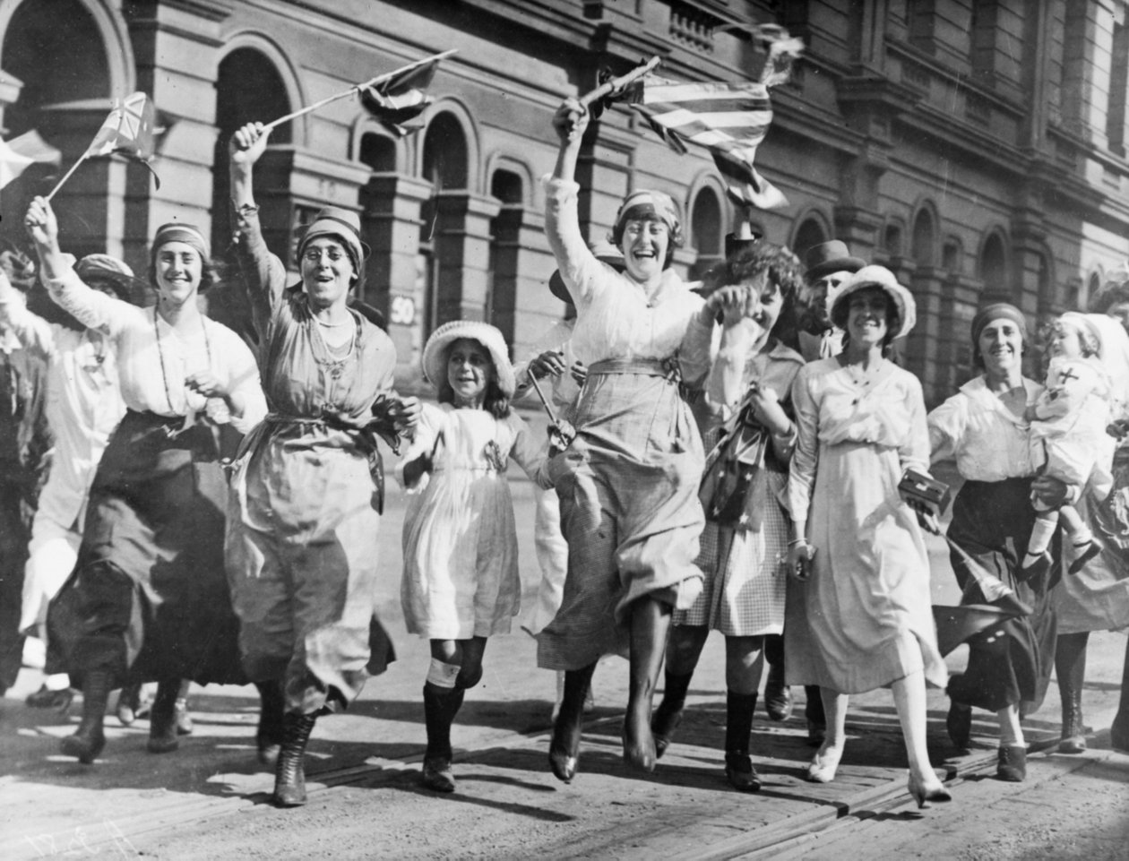 Ryhmä naisia ja lapsia iloitsemassa kadulla Sydneyssä aselevon allekirjoittamisen yhteydessä 11. marraskuuta 1918 tekijältä Australian Photographer