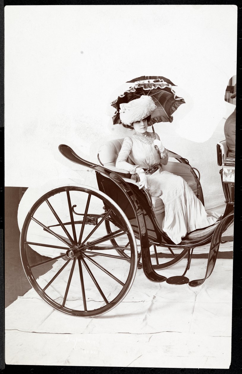 Malli istuu vaunuissa aurinkovarjoa kädessään, 1902 (hopeagelatiiniprintti) tekijältä Byron Company