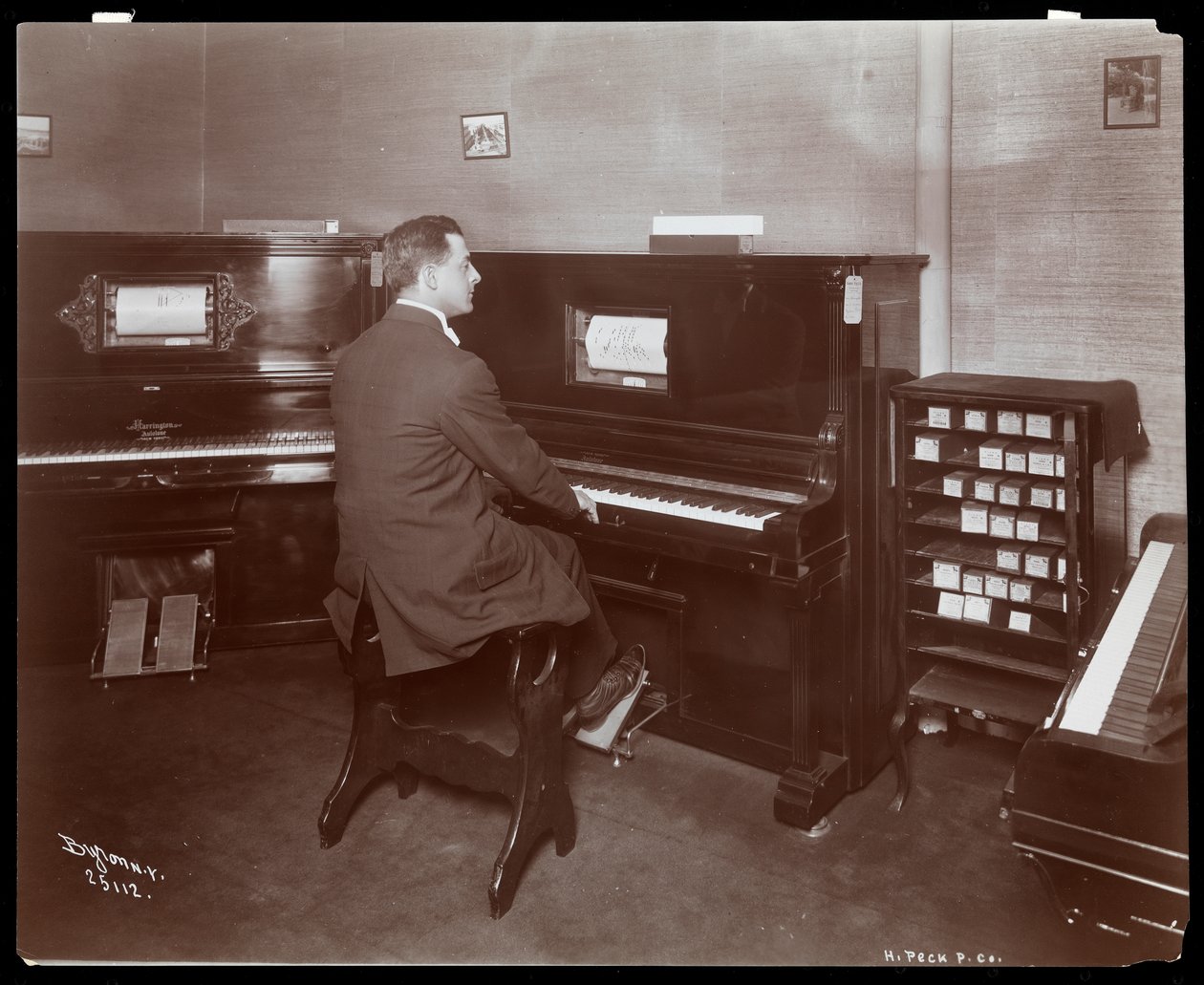 Mies soittaa pianosoitinta pianonäyttelyssä New Yorkissa, 1907 (hopeagelatiiniprintti) tekijältä Byron Company