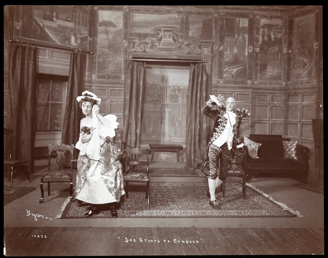 Kohtaus harrastajatuotannosta "She Stoops to Conquer" (hopeagelatiinipaino). tekijältä Byron Company