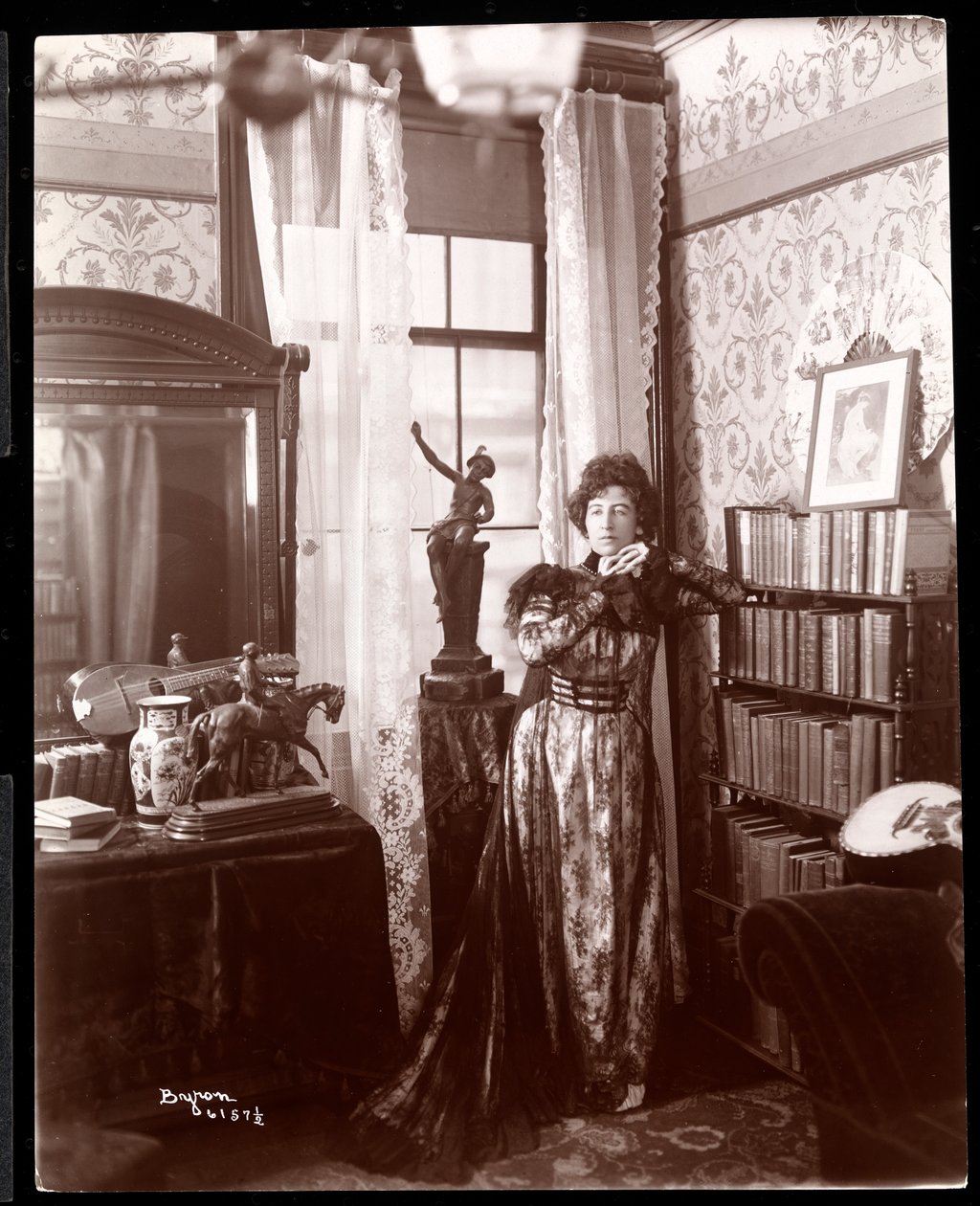 Anita Chartres seisoo huoneen nurkassa, noin 1898 (hopeagelatiinivedos). tekijältä Byron Company