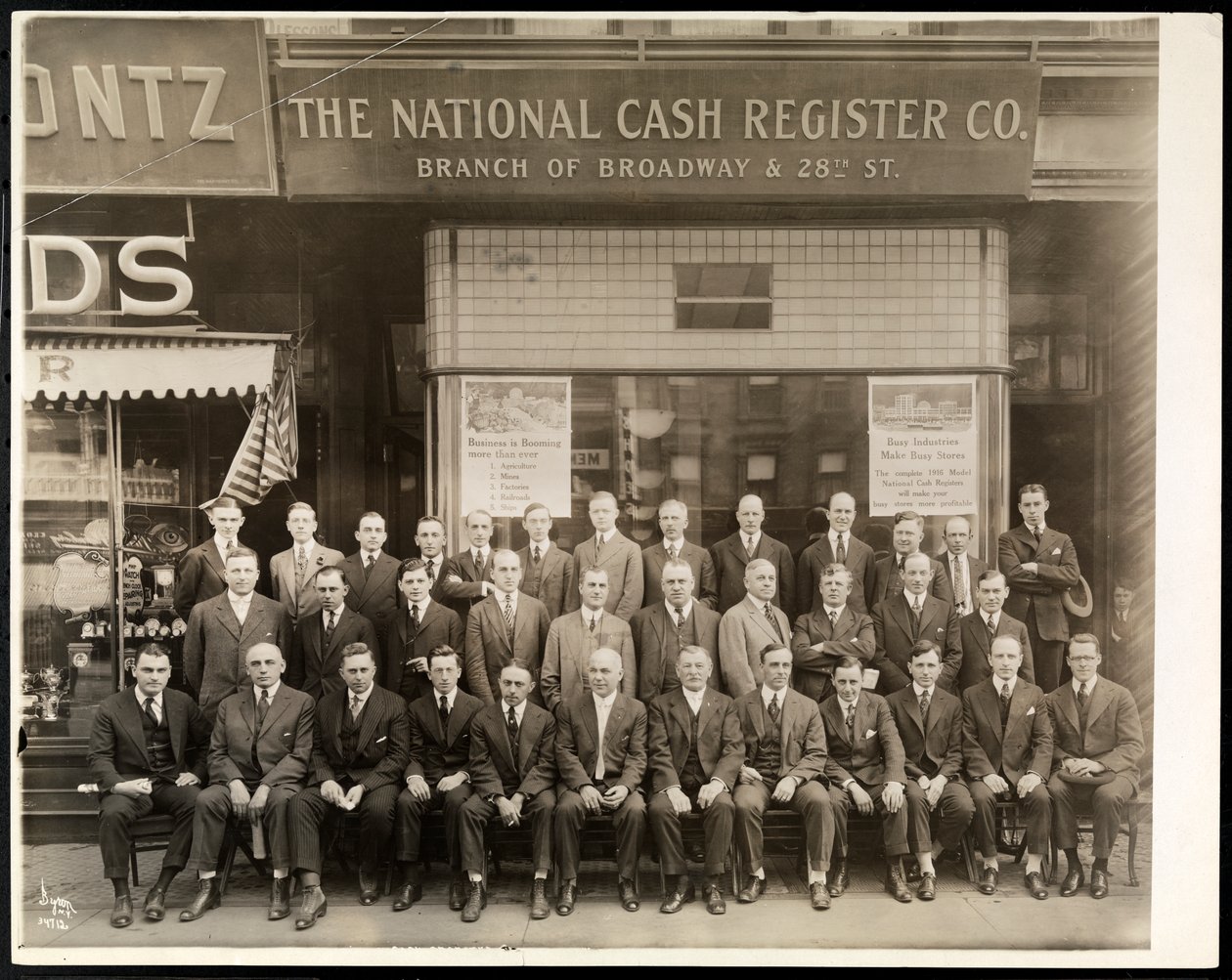Ryhmä National Cash Register Co.:n miehiä poseerasi Broadwayn ja 28th Streetin haarakonttorin edessä New Yorkissa, 1916 (hopeagelatiiniprintti) tekijältä Byron Company