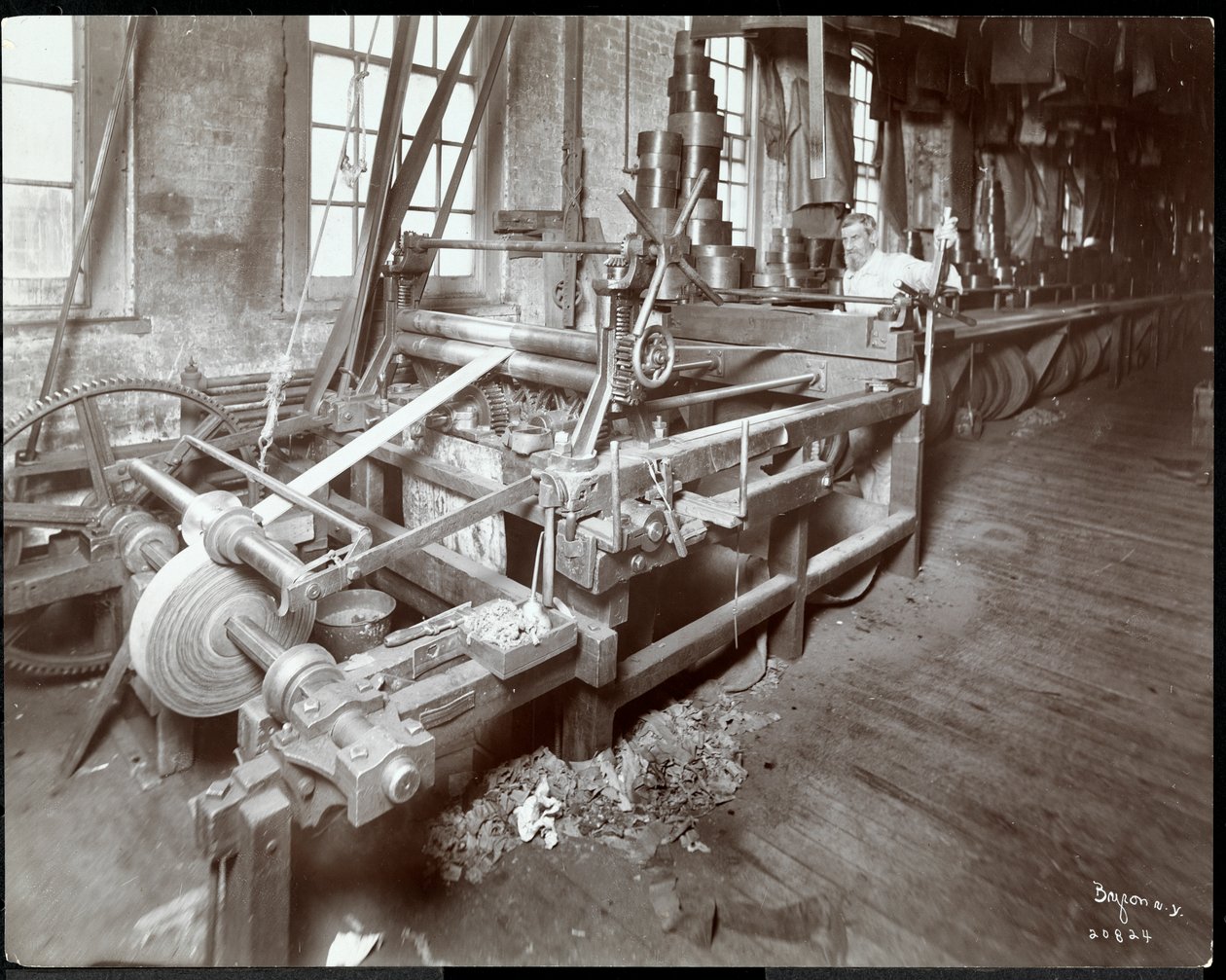 Sisäkuva miehestä, joka työskentelee nahan kanssa New York Leather Belting Co:ssa, New York, 1906 (hopeagelatiinivedos). tekijältä Byron Company
