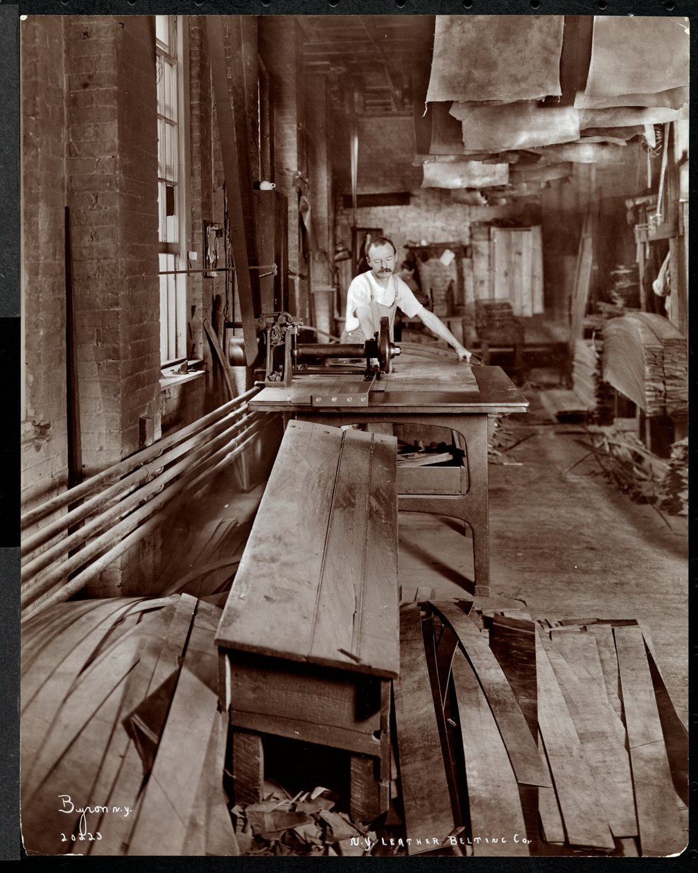 Sisäkuva miehestä, joka työskentelee nahkaa New York Leather Belting Co.:ssa, New York, 1905 (hopeagelatiiniprintti) tekijältä Byron Company