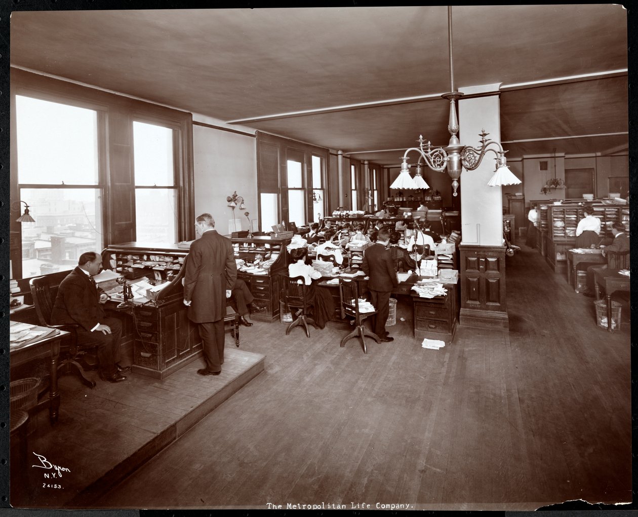 Miehet ja naiset työskentelevät työpöydän ääressä Metropolitan Life Insurance Co:n toimistossa osoitteessa 23rd Street ja Madison Avenue, New York, 1907 (hopeagelatiiniprintti) tekijältä Byron Company