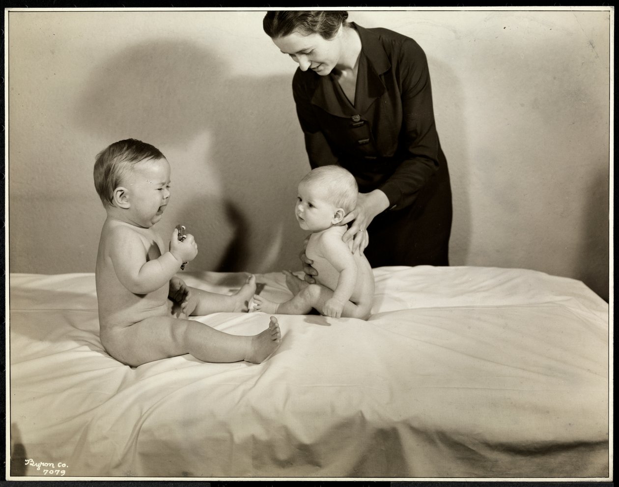 Kaksi vauvaa istuu sängyssä, joista toista tukee sairaanhoitaja, toisella leluauto ja itkeminen Maternity Center Associationissa osoitteessa 70th Street East River, New York, 1935 (hopeagelatiiniprintti tekijältä Byron Company