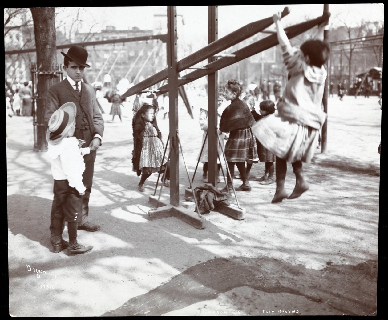 Näkymä miehestä, joka valvoo leikkikenttälaitteilla leikkiviä lapsia Tompkins Square Parkissa, Arbor Day, New York, 1904 (hopeagelatiiniprintti) tekijältä Byron Company