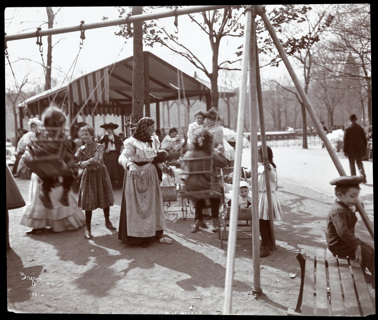 Näkymä naisesta, joka työntää lapsia keinuissa Tompkins Square Parkissa, Arbor Day, New York, 1904 (hopeagelatiiniprintti) tekijältä Byron Company