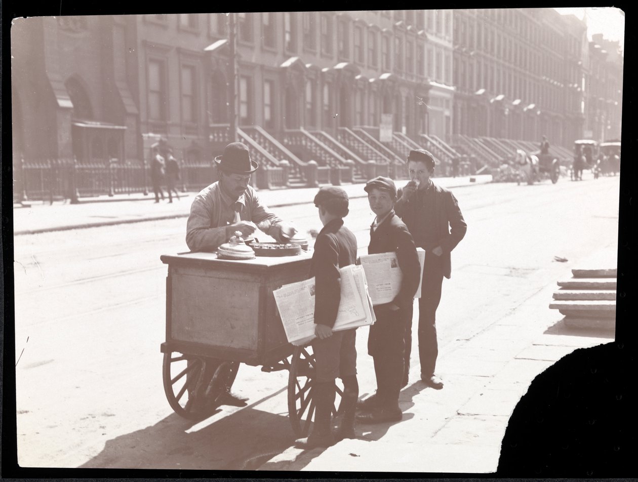 Näkymä jäätelökauppiasta kadulla, jossa kolme sanomalehtipoikaa ostamassa jäätelöä, New York, n. 1901 (hopeagelatiiniprintti) tekijältä Byron Company