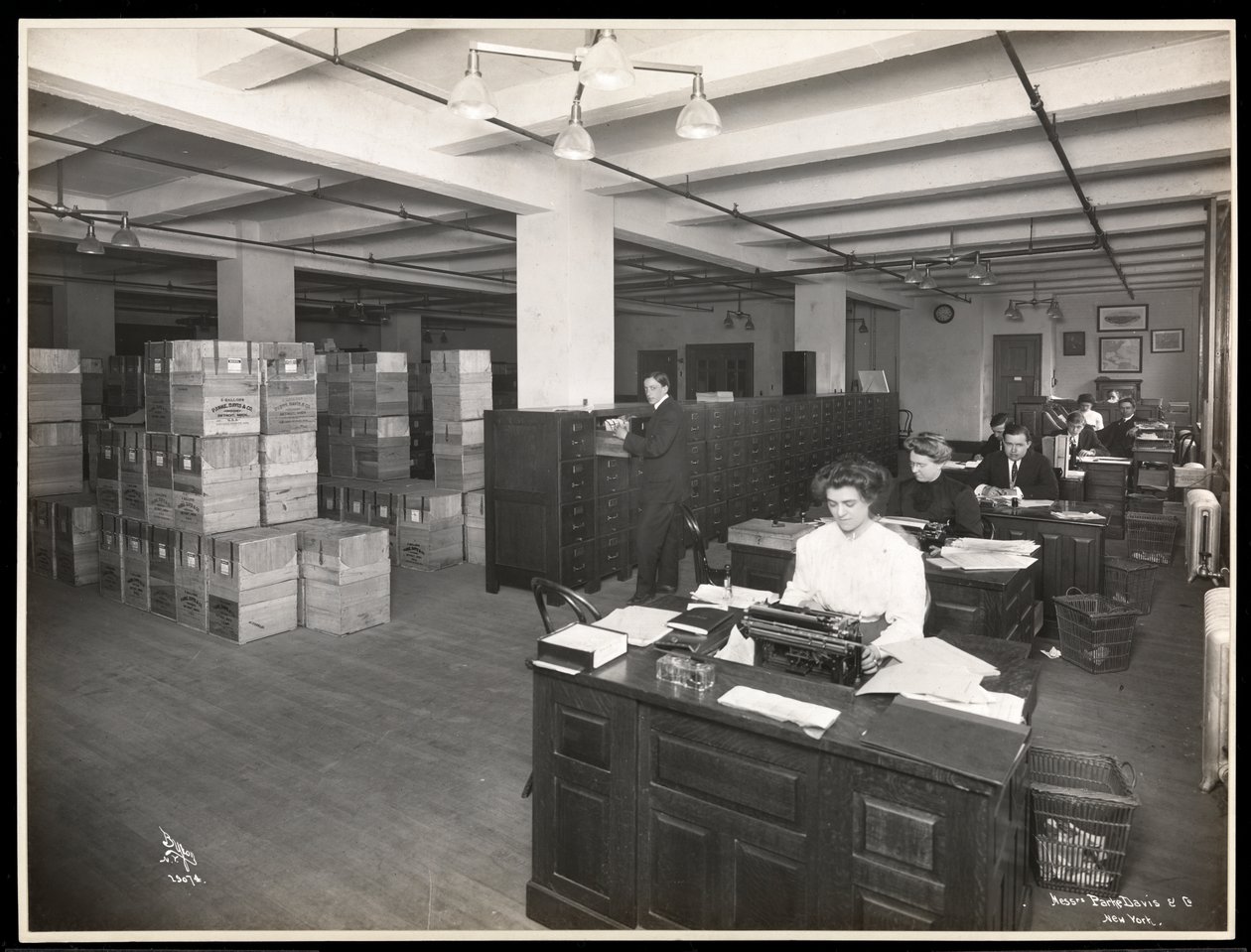 Näkymä miehistä ja naisista työpöydän ääressä kuljetushuoneelta Parkessa, Davis und Co., kemistit, Hudson und Vestry Streets, New York, 1910 (hopeagelatiiniprintti) tekijältä Byron Company