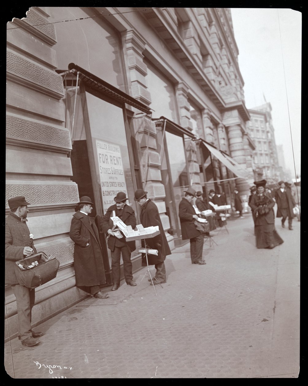 Näkymä kauppiaista, jotka myyvät leluja ja muita esineitä Fuller- tai Flatiron Buildingin edessä osoitteessa Broadway, 5th Avenue ja 23rd Street, New York, n. 1895 (hopeagelatiiniprintti) tekijältä Byron Company
