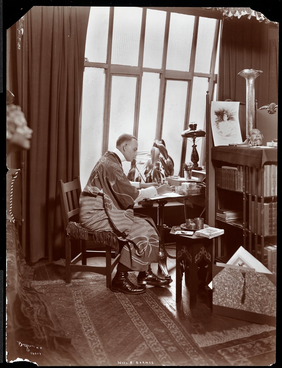 Will R. Barnes kaapussa, istuu työpöytänsä ääressä studiossaan, 1903 (hopeagelatiiniprintti) tekijältä Byron Company