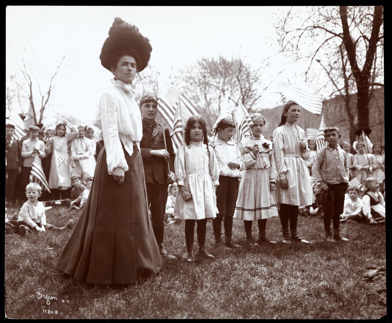 Nainen lasten kanssa pitelemässä lippuja Arbor Dayna Tompkins Square Parkissa, New Yorkissa, 1904 (hopeagelatiiniprintti) tekijältä Byron Company
