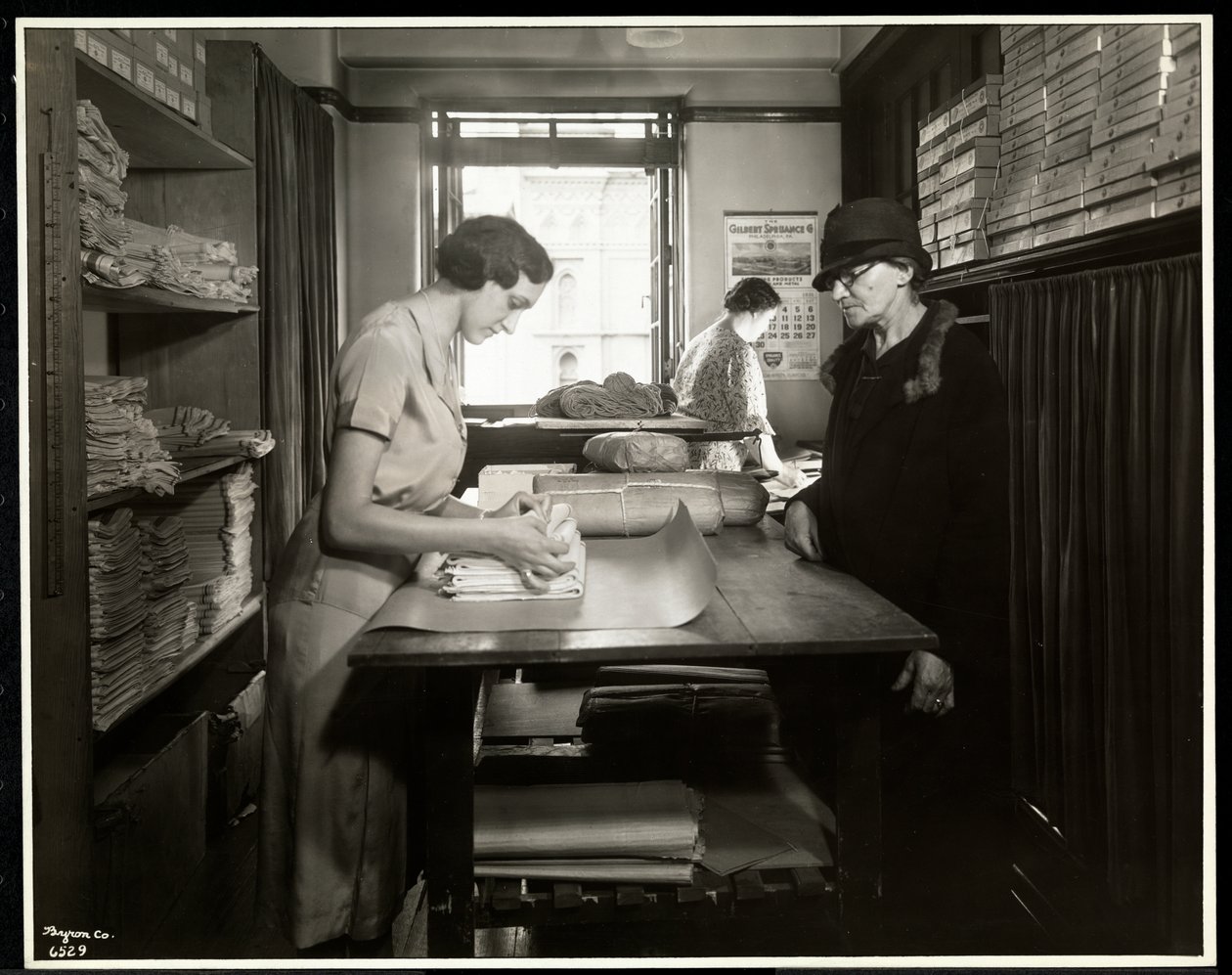 Nuori nainen käärimässä kangasmateriaaleja kotityöntekijälle mukanaan New York Association for the Blindissa, 111 East 59th Street, New York, 1931 (hopeagelatiiniprintti) tekijältä Byron Company