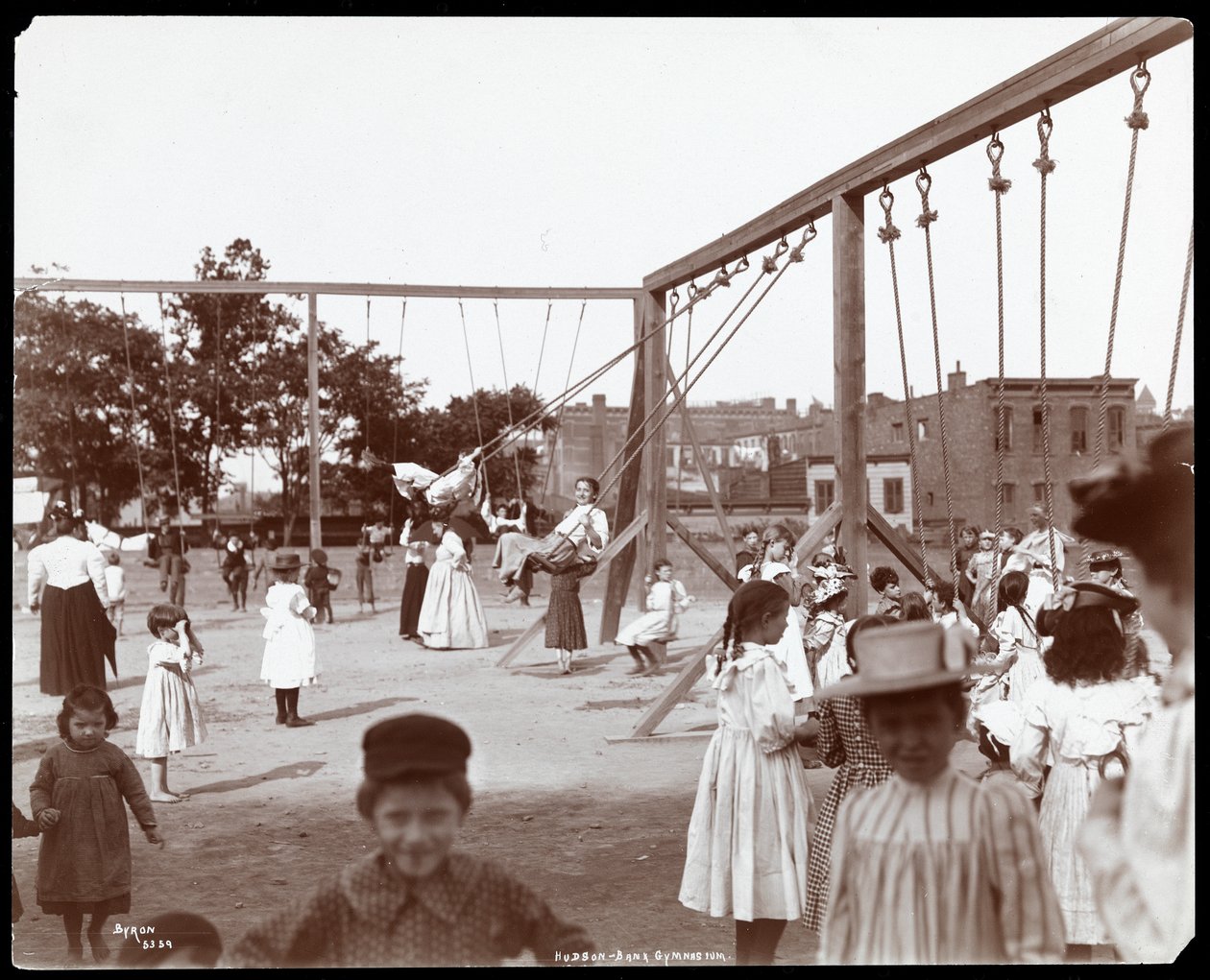Lapset keinuvat Hudson Bank Gymnasiumissa ja leikkikentällä, 53rd Streetin ja 11th Avenuen kulmassa, New York, 1898 (hopeagelatiinivedos). tekijältä Byron Company