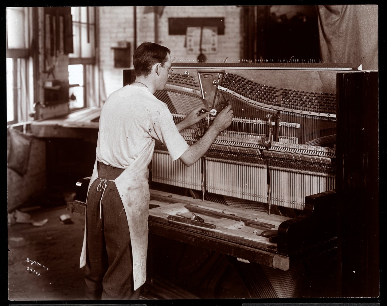 Mies työskentelee Hardman, Peck und Co:n pianotehtaalla, New York, 1907 (hopeagelatiiniprintti) tekijältä Byron Company