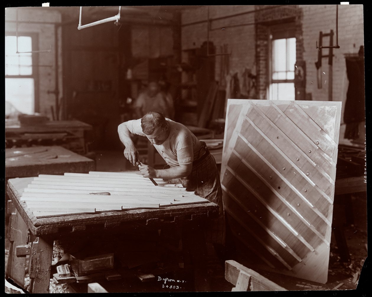 Mies työskentelee Hardman, Peck und Co:n pianotehtaalla, New York, 1907 (hopeagelatiiniprintti) tekijältä Byron Company