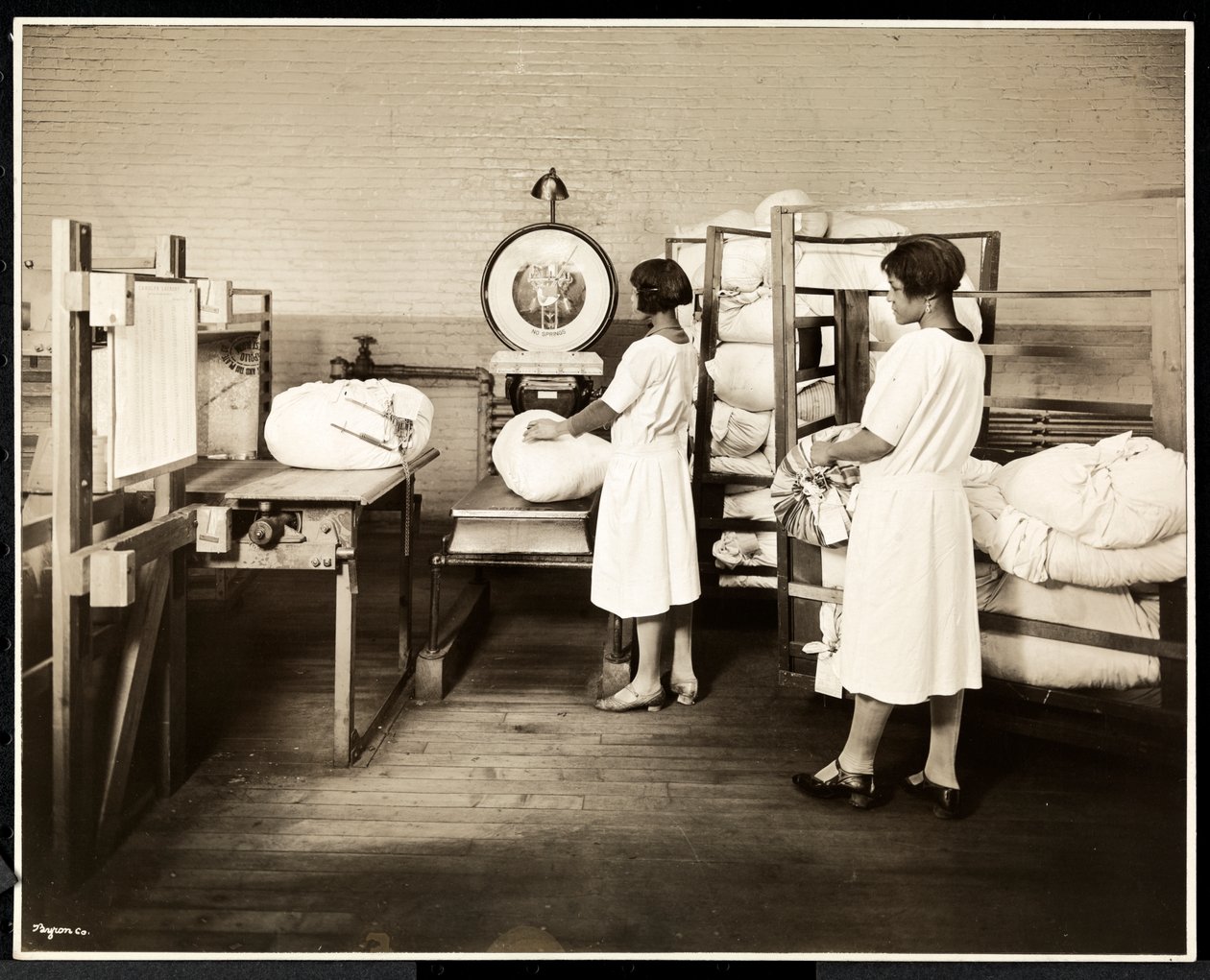 Kaksi afroamerikkalaista naista punnitsemassa pussia pyykkiä Carolyn Laundryssa osoitteessa 111 East 128th Street, East Harlem, New York, 1928 (hopeagelatiiniprintti) tekijältä Byron Company
