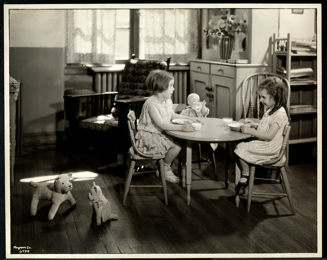 Kaksi sokeaa näkövammaista tyttöä syömässä pienen pöydän ääressä nuken kanssa New York Association for the Blindissa, 111 East 59th Street, New York, 1933 (hopeagelatiiniprintti) tekijältä Byron Company