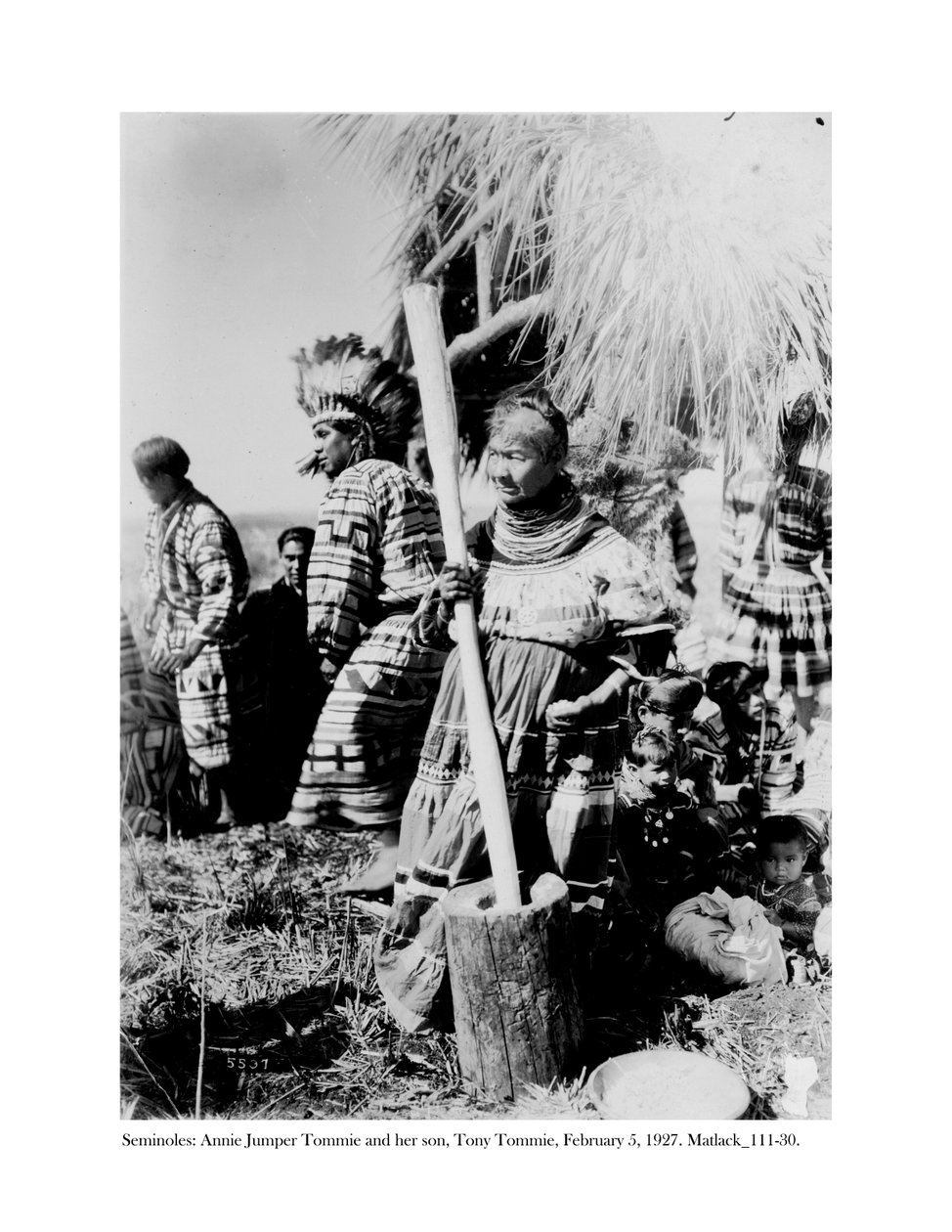 Annie Jumper Tommie käytti huhmaretta ja survinta maissijauhojen valmistukseen, ja hänen poikansa Tony Tommie kotkan höyhenpäällään, 5. helmikuuta 1927 tekijältä Claude C. Matlack