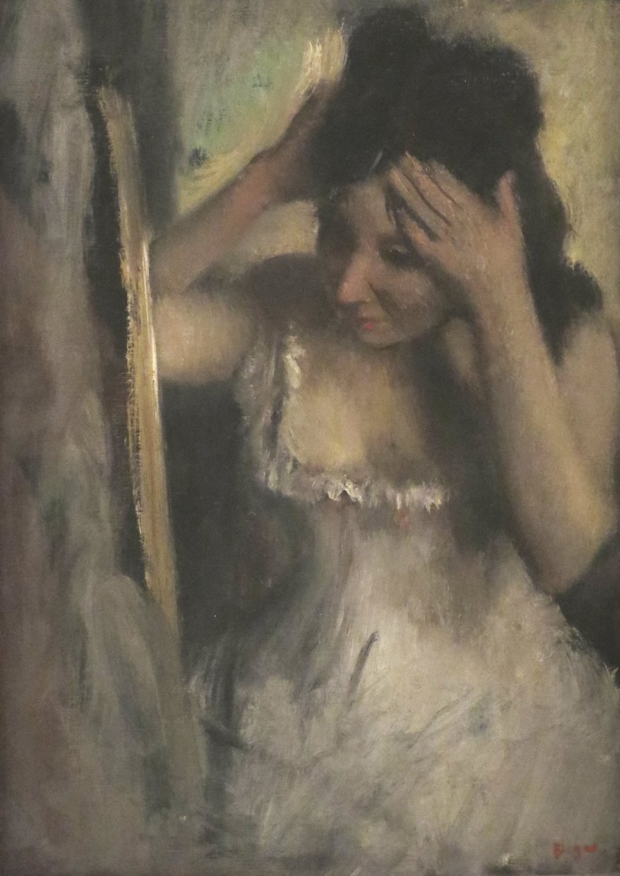 Nainen kampaa hiuksiaan peilin edessä tekijältä Edgar Degas