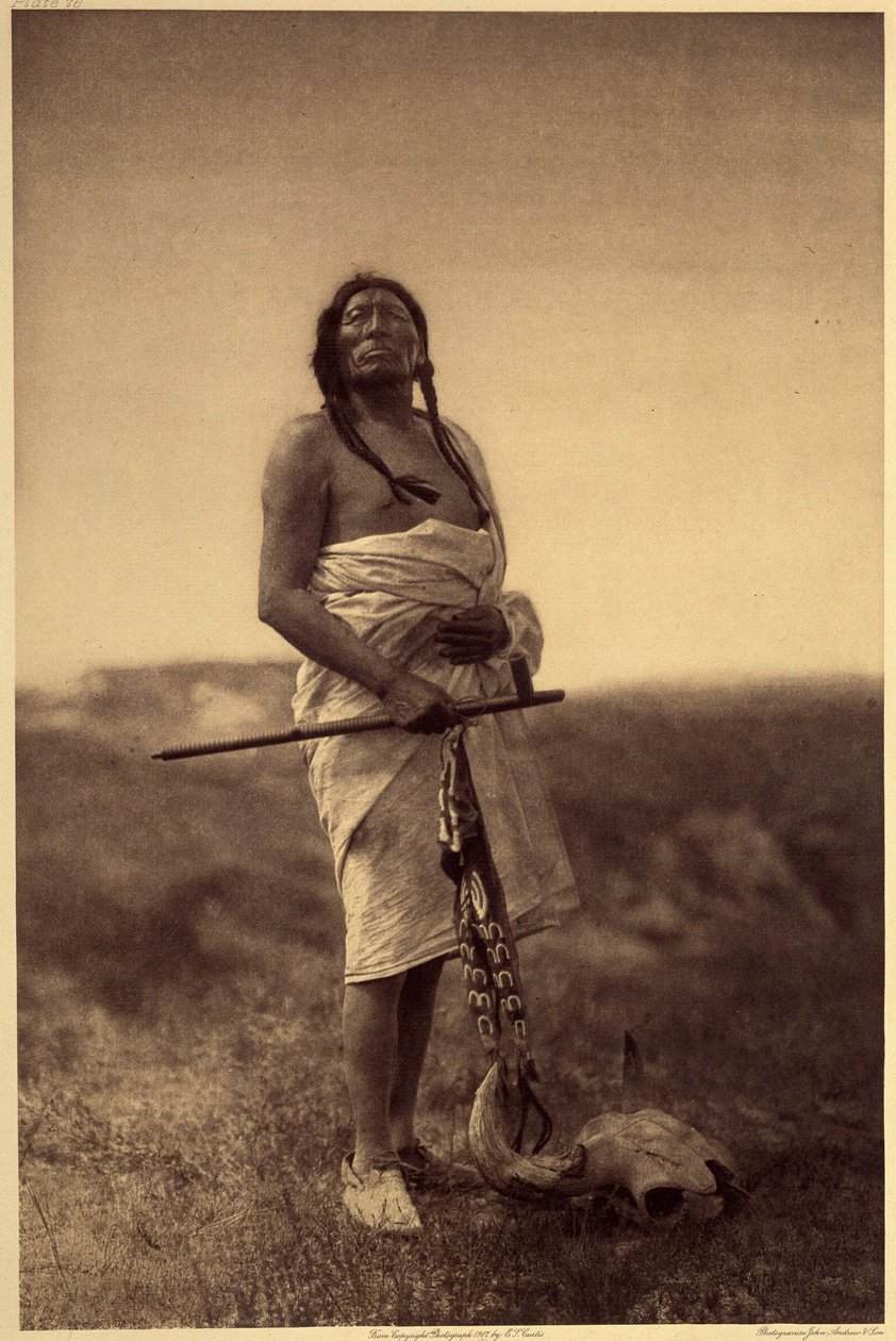 Mies lääkäri. Luultavasti Sioux, kalmari kädessään ja puhvelin kallo on jalat. Kuva otettu osasta 3 Edward S. Curtisin tietosanakirjasta (1868-1952) Pohjois-Amerikan intiaaneista, esipuheella Theodore Roosevelt. Vuosina 1907-1930 julkaistiin 20 osaa tekijältä Edward Sheriff Curtis