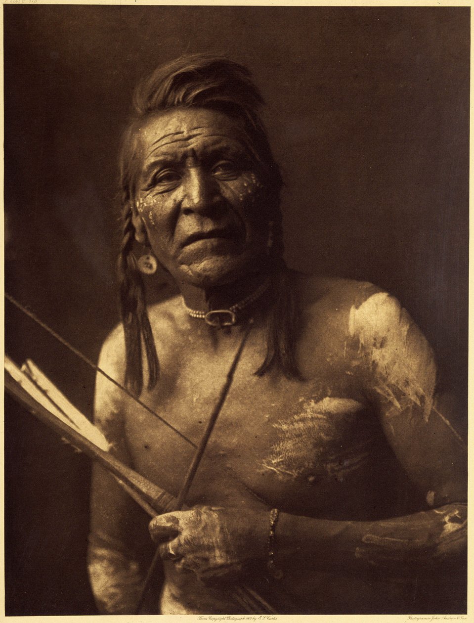 Two Leggings, Apsaroke, teki noin 1848. Hänen visionsa eivät antaneet hänelle suuria voimia, ja Bull Goes Hunting hyväksyi hänet salaiseen tupakkayhdistykseen, joka antoi hänelle fossiilista tai karkeasta kivestä tehdyn amuletin muodossa. kaksipuolinen hev tekijältä Edward Sheriff Curtis