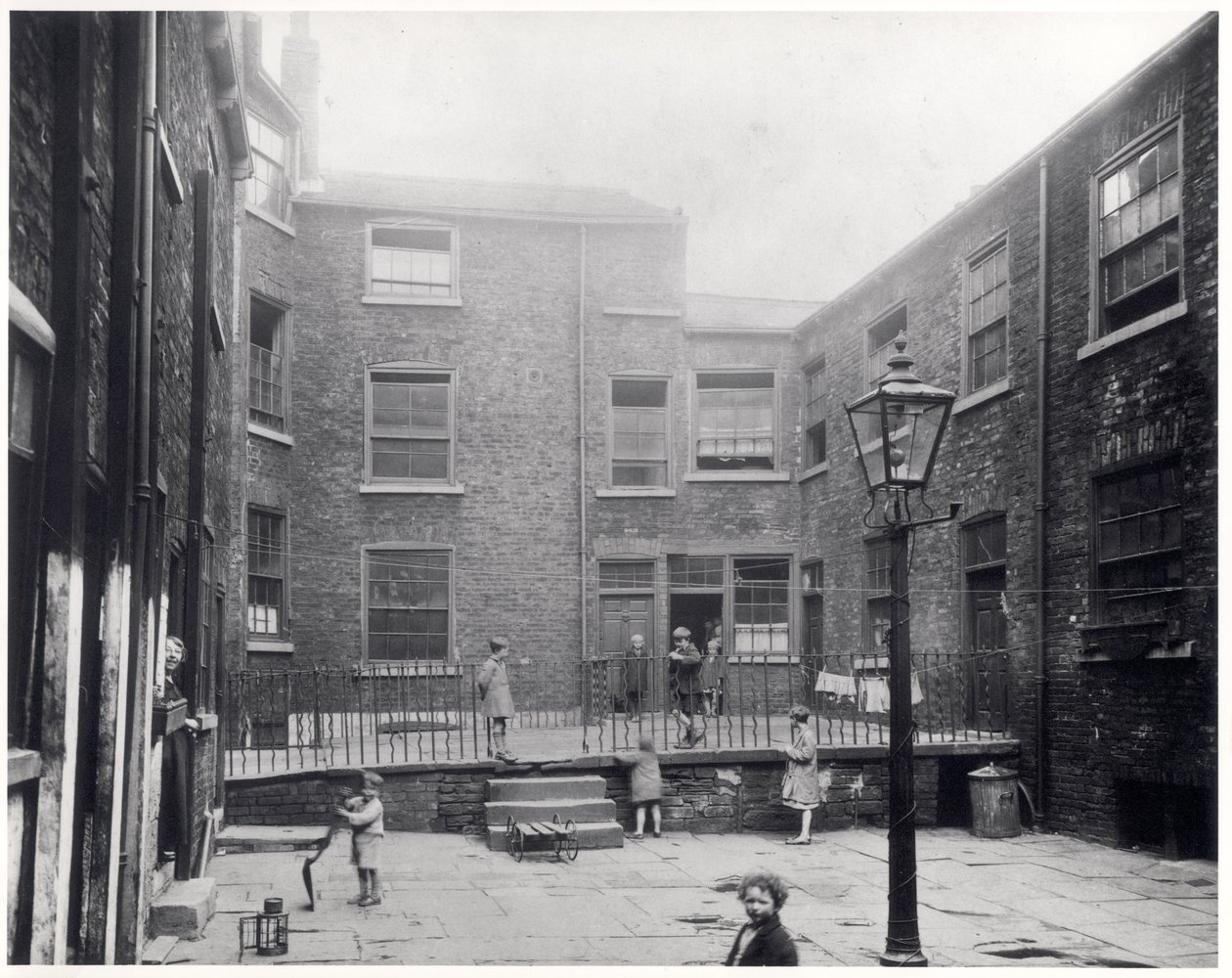 Lapset leikkivät Hirst Squarella Leedsissä, ennen kuin se purettiin uuden Civic Hallin tieltä, 29. heinäkuuta 1930 tekijältä English Photographer
