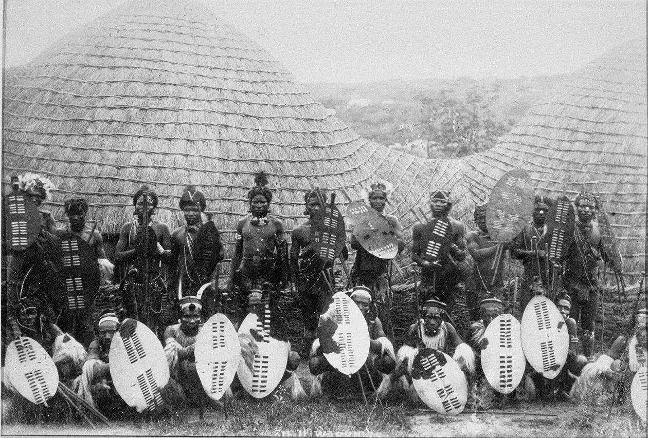 Zulusotureiden ryhmämuotokuva kotan ulkopuolella, n. 1875 (albumiprintti) tekijältä English Photographer