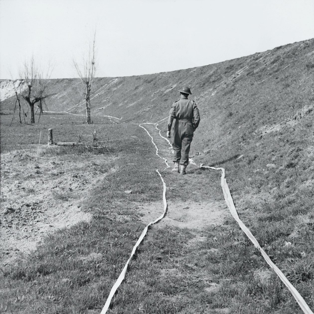 Valkoinen teippi merkitsee selkeitä jälkiä miinakentän läpi Senio-joen varrella, Italiassa, maaliskuu 1945 tekijältä English Photographer