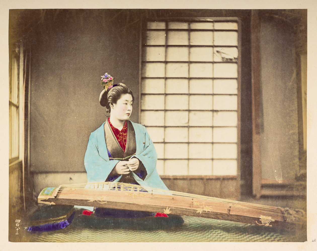 Laulavat tytöt [Japani], Studiomuotokuva japanilaisesta naisesta, joka istuu kielisoittimella (eräänlainen kantele) lepäämässä lattialla edessään,  Valokuvaaja: Tuntematon  Lucas Collection: Valokuvaennätys Charles Jamesin ja Mo:n maailmankiertueesta tekijältä English Photographer
