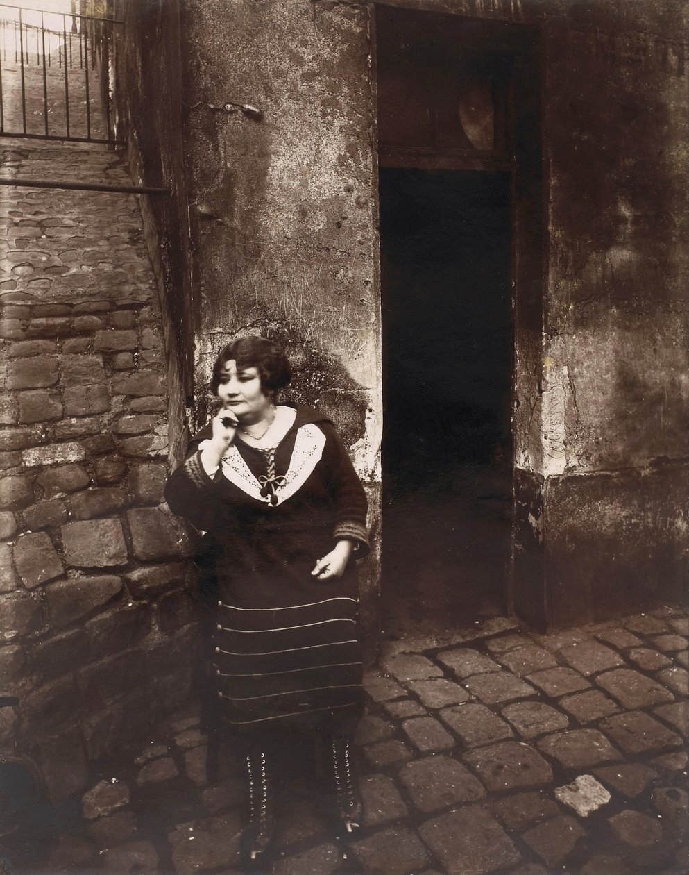 La Villette. Rue Asselin, prostituoitu odottaa ovensa edessä. tekijältä Eugène Atget