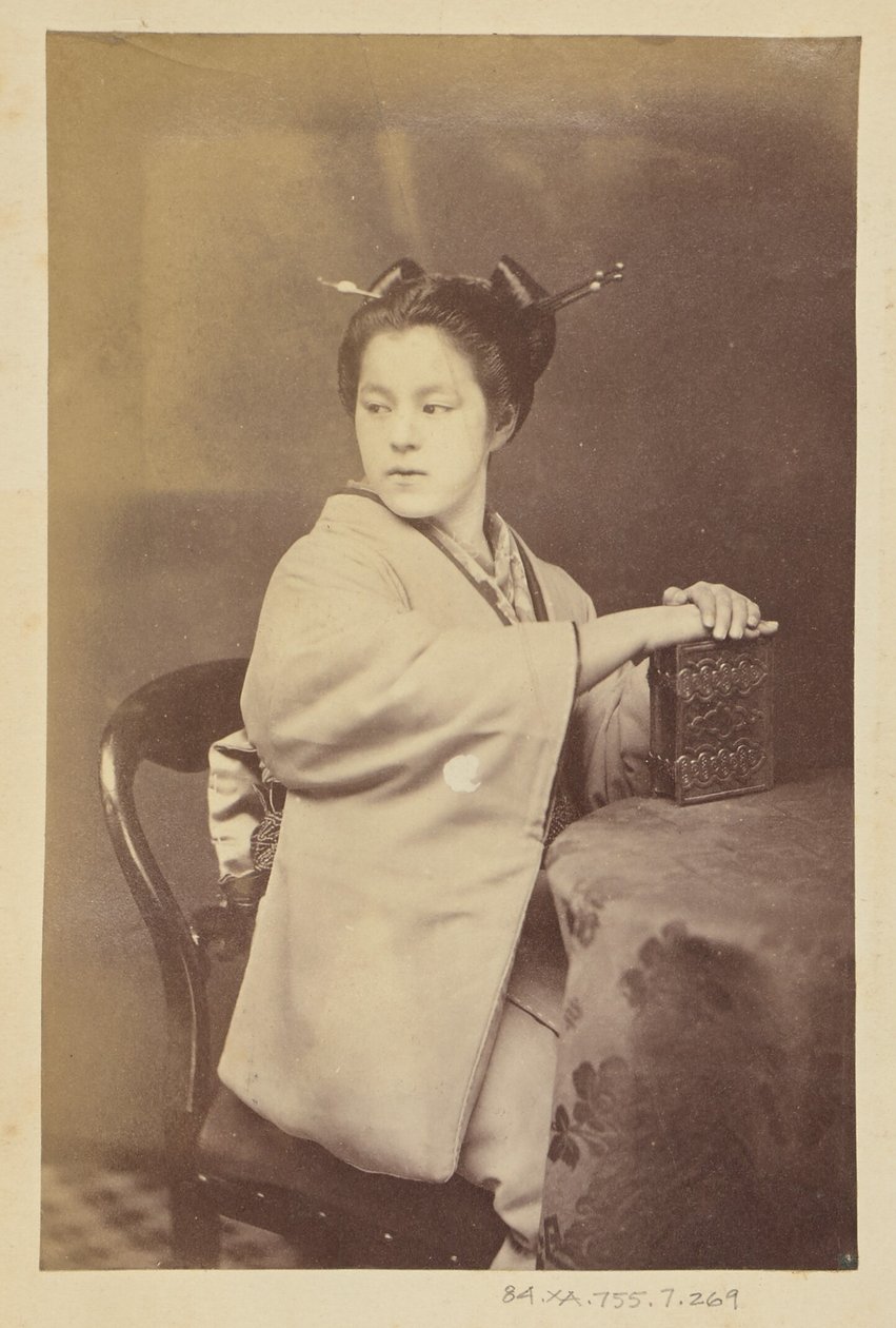 [Istuva japanilainen nainen pitelee pöydän ääressä cartes-de-visite-albumia] tekijältä Felice Beato