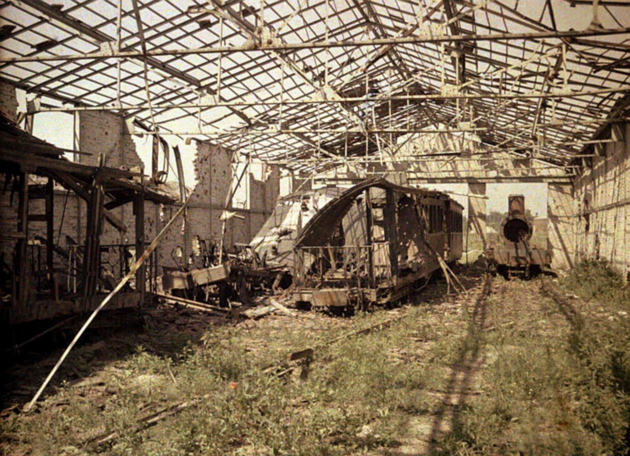 Palanut rautatie- ja raitiovaunupiha, jossa on muutamia vaurioituneita ajoneuvoja ja veturi, Soissons, Aisne, Ranska, 1917 (autokromi) tekijältä Fernand Cuville
