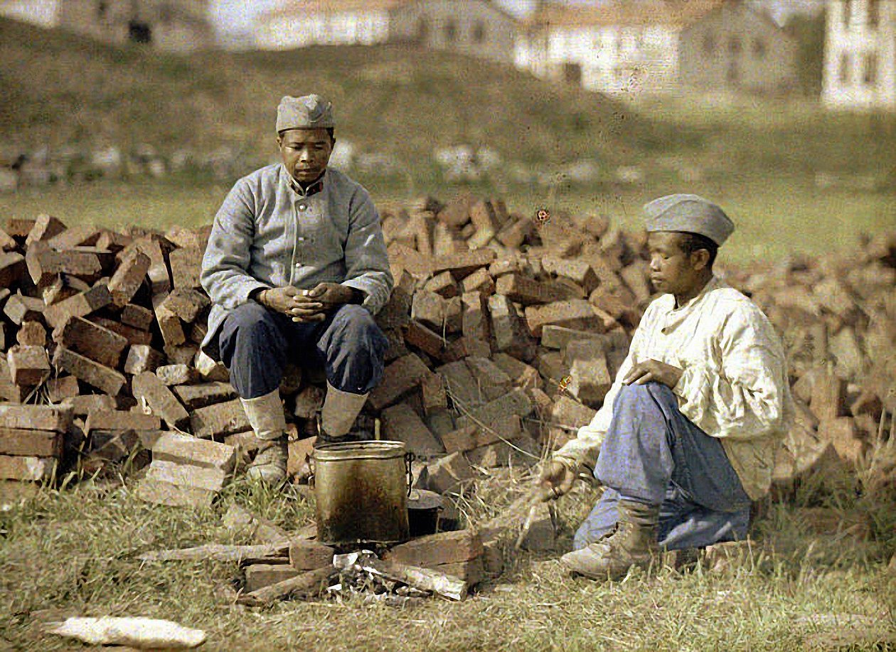 Kaksi afrikkalaista sotilasta lämmittelemässä ateriaa, Soissons, Aisne, Ranska, 1917 (autokromi) tekijältä Fernand Cuville