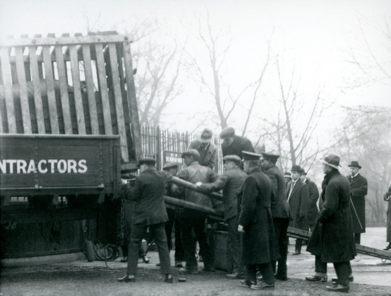 Joukko katsojia seisoo paikalla, kun sarvikuono lastataan kuorma-autosta Lontoon eläintarhassa vuonna 1924. tekijältä Frederick William Bond