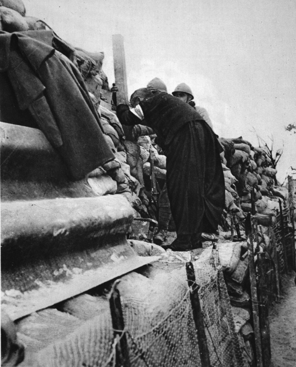 Ranskalainen pappi rivissä: parannuskeino, joka kurkistaa kaivannon periskoopin läpi, kuva The Illustrated War Newsista, 31. tammikuuta 1917 tekijältä French Photographer