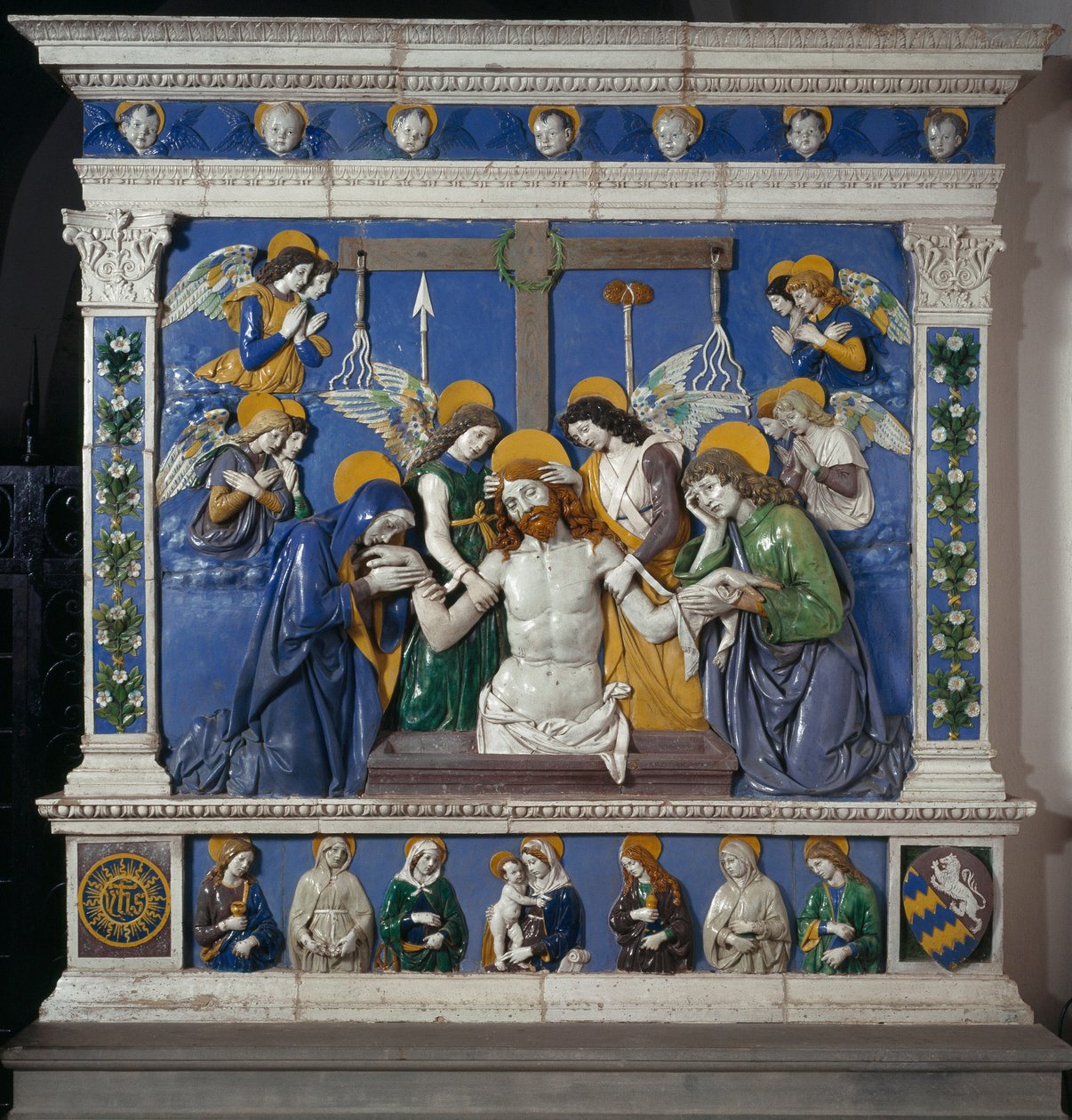 Jeesuksen asettaminen Pyhälle haudalle Neitsyt ja Pyhän Johanneksen evankelista Kuvaus kärsimyksen symboleista: ruoskat, orjantappurakruunu ja etikkaan kastettu sieni (posca). Giovanni della Robbian (1469-1529) korkeareliefikeramiikka noin 14 tekijältä Giovanni della Robbia