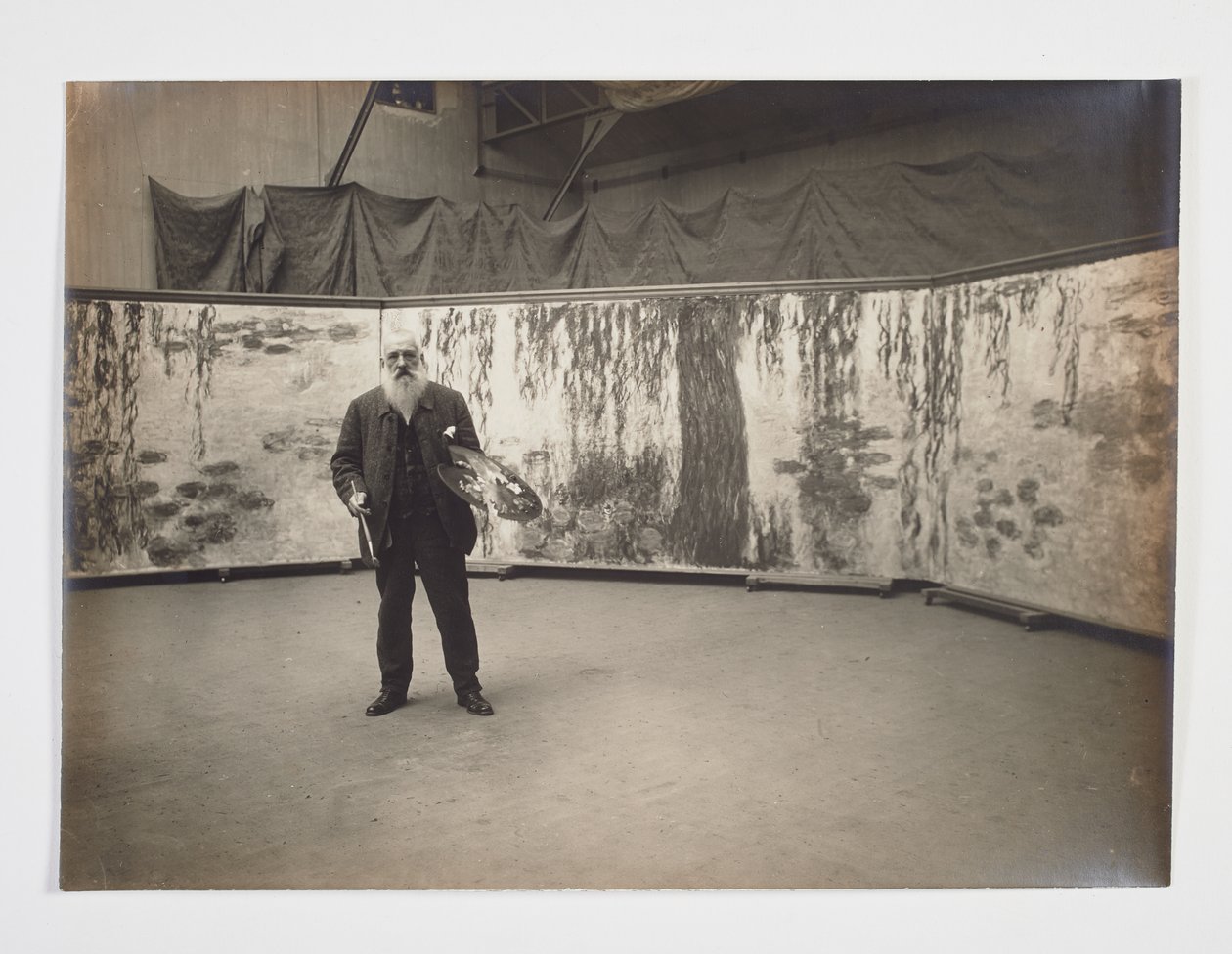 Claude Monet palettillaan Les nymphéas -teoksensa edessä tekijältä Henri (attr. to) Manuel