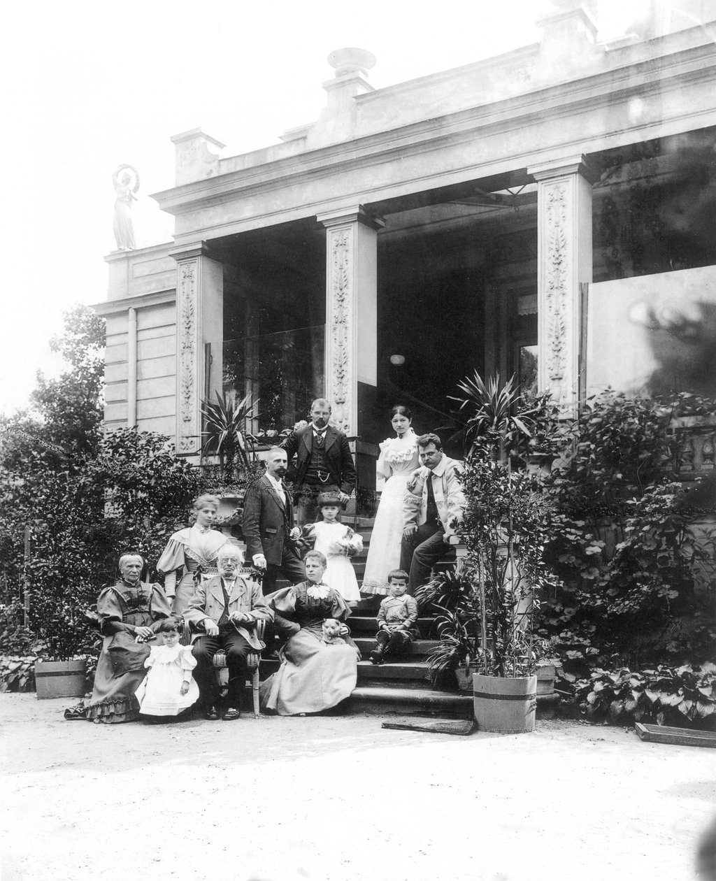 Max Klinger (1857-1920, kuvassa ylhäällä vasemmalla) perheensä kanssa vanhempiensa talon edessä Leipzigissä, Karl-Heine-Strasse 2 (puutarhan puolella) tekijältä Hermann Walter