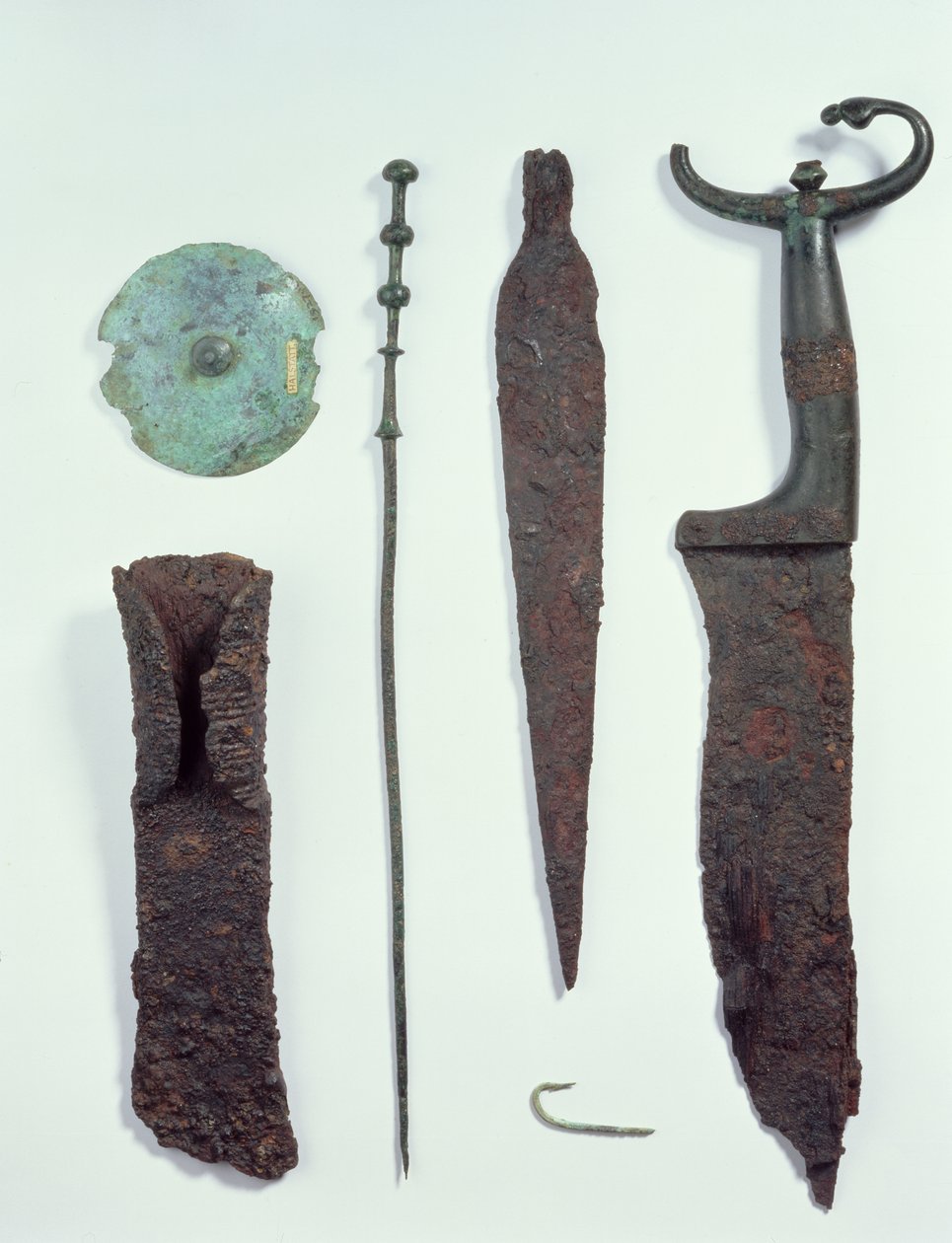 Ylhäältä alas: veitsi, keihäänkärki, koukku, pyykkipuikko, vyökiekko ja kirves, kaikki löytyi rautakauden Hallstattin mieshaudoista tekijältä Iron Age