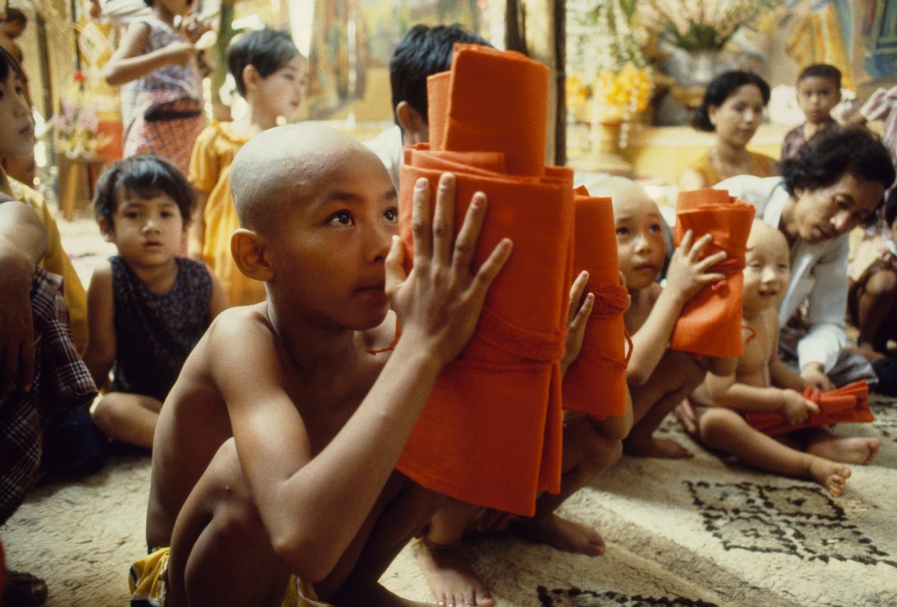Nuori poika, jolla on ajeltu pää, saa munkkivaatteensa. Mandalay, Burma. tekijältä James L Stanfield